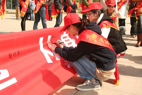 志愿者们在“学雷锋从身边事做起”的横幅上签名